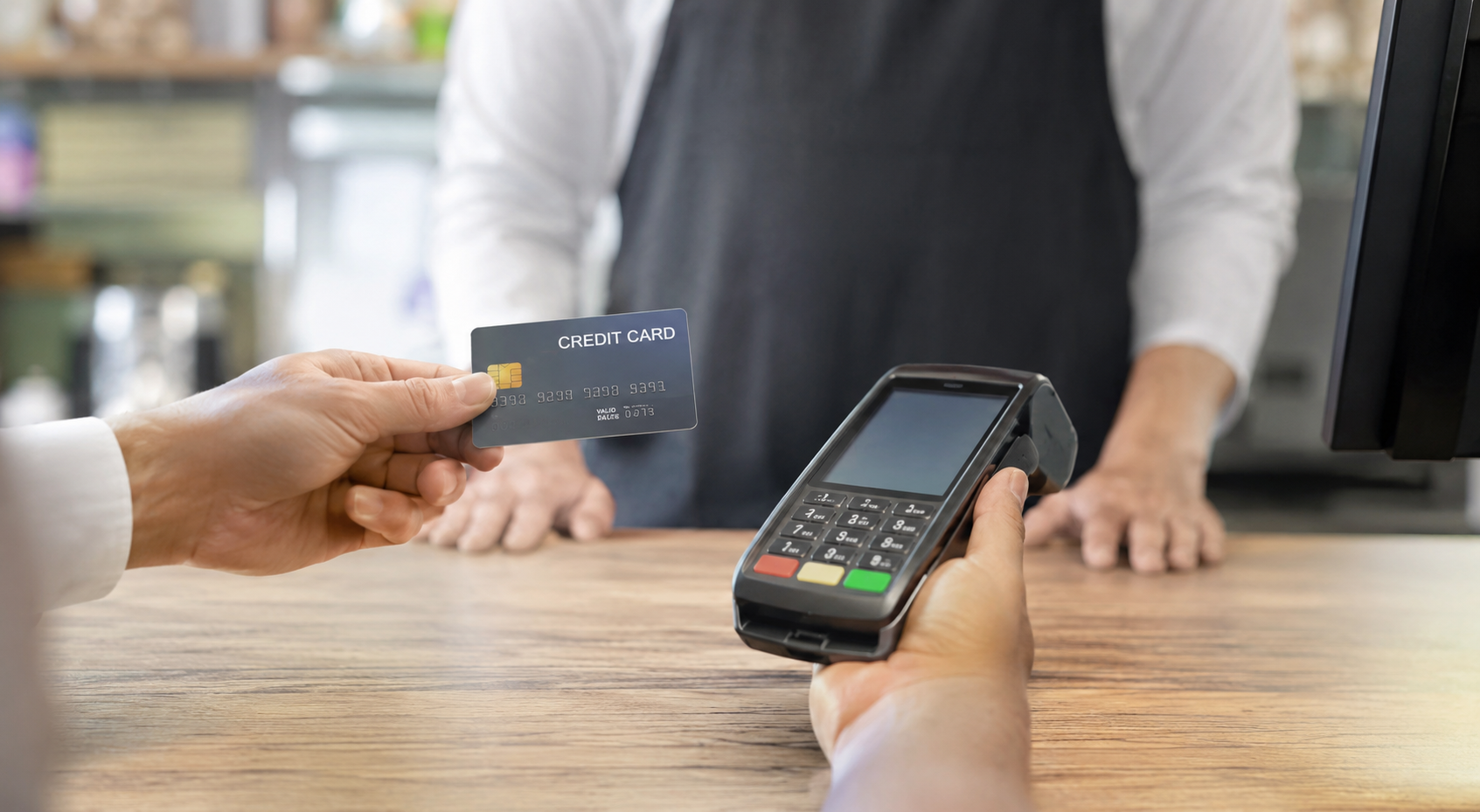 Credit card being processed through a payment terminal at a retail checkout counter.